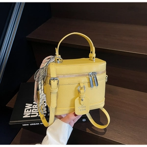Détail du sac boîte en cuir jaune avec fermeture éclair argentée et breloque raquette