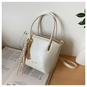 Detailed view of the cream white PU bucket bag featuring gold chain and brand logo engraving