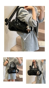 Detail of black patent leather bowling bag with monkey charm and pearl chain decoration