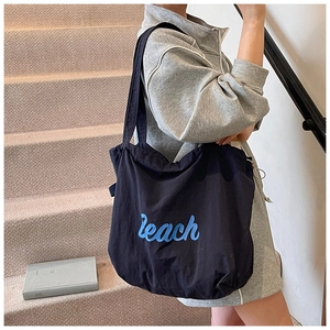 Close-up of a black canvas tote bag featuring blue Peach lettering on a wide shoulder strap