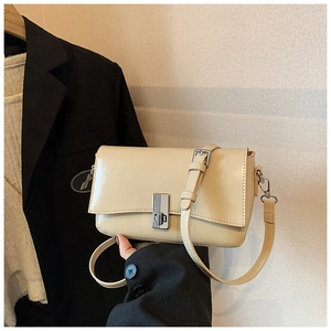 Close-up of a beige oil wax leather square crossbody bag with silver metallic hardware