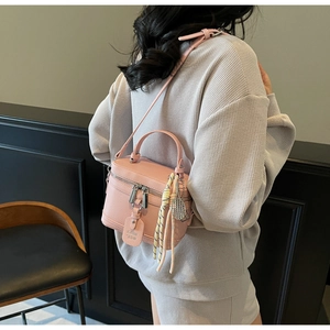 Détail d'un sac boîte rose avec texture litchi et pendentif de raquette de tennis