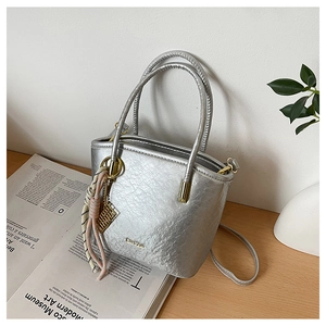 Detail of silver textured mini bucket bag with silk scarf charm and gold logo