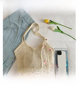 Detail of beige hollow woven tote bag with white floral embroidery lace scarf accessory