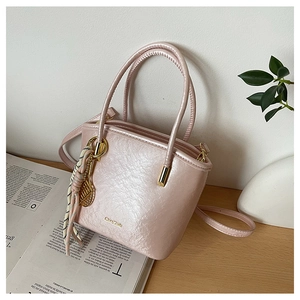 Detail of pink pearlescent mini bucket bag with gold lettering and tennis racket charm