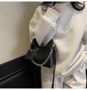Detailed view of black litchi texture leather bucket bag with silver chain strap handle
