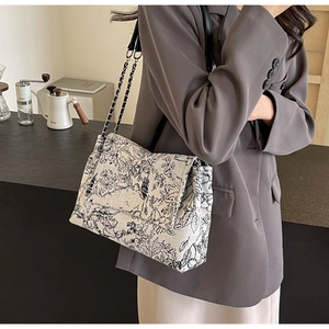 Close-up of black and white Toile de Jouy print tote with silver chain shoulder strap