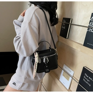 Détail du sac bandoulière en cuir noir avec ferrures argentées et pendentif raquette