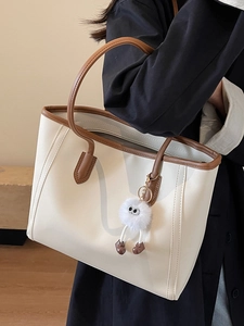 Minimalist cream tote bag with brown contrast trim and plush doll charm for women