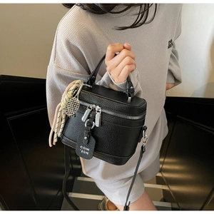Détail du sac boîte noir avec texture litchi, double fermeture éclair et pendentif