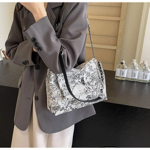 Detail of floral canvas tote bag with black leather strap and silver chain accent