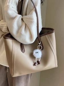 Stylish large capacity contrast color tote bag with plush charm on a beige sweater model