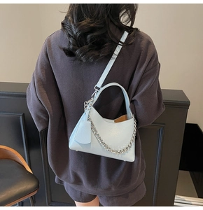 Close-up of light blue lychee pattern leather bucket bag with silver chain detail on model