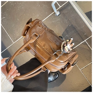 Close-up of vintage brown bowling bag with glossy finish and cute doll pendant detail