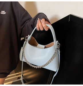 Detail of light blue lychee texture bucket bag with chunky silver chain and strap