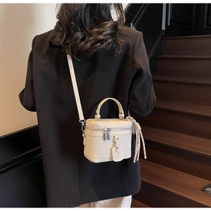 Sac boîte blanc crème avec texture litchi porté par un mannequin en intérieur moderne