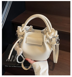 Close-up of lychee grain cream bucket bag with pleated design and pearl bow charms