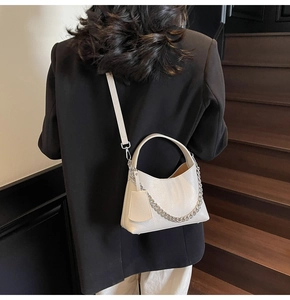 Close-up of cream textured leather bucket bag with silver chain and side charm detail