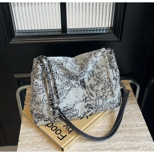 Detail of artistic floral canvas tote bag with silver chain strap and leather finish