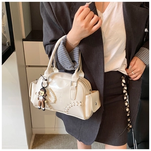 Detail of white vintage bowling bag with decorative stitching and pearl keychain charm