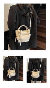 Detailed macro view of cream-colored lychee pattern leather bucket bag with pearl pendant