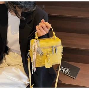 Détail du sac boîte jaune vif en cuir grainé avec fermeture éclair argentée et pendentif