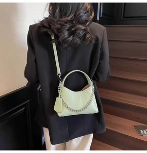 Close-up of light green lychee textured bucket bag with silver chain and shoulder strap