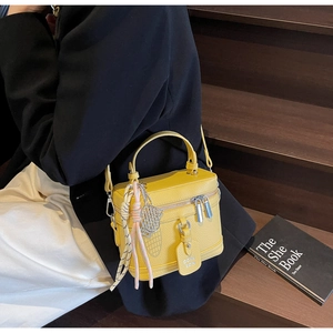 Détail d'un sac boîte jaune à texture litchi avec bandoulière réglable porté par un mannequin