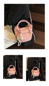 Macro shot of pink lychee grain leather bucket bag with bow pearl pendant and strap