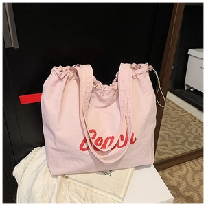 Detail of light pink tote bag with red Reach lettering and adjustable drawstring closure
