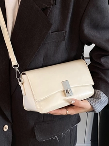 Minimalist cream oil wax leather crossbody bag for women with silver buckle on a stylish suit