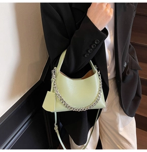 Detail of light green bucket bag with lychee texture and silver chain strap on model