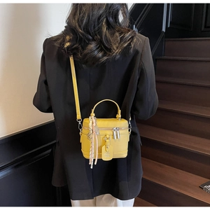Sac boîte jaune vif en cuir grainé avec foulard décoratif porté par un mannequin