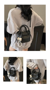 Detail of black lychee grain bucket bag with pearl charm and checkered ribbon bow accessory