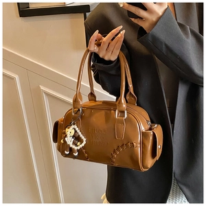 Brown vintage bowling bag in glossy leather with embossed letters and cute doll charm