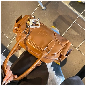 Close-up of brown bowling bag with monkey charm and pearl chain decoration