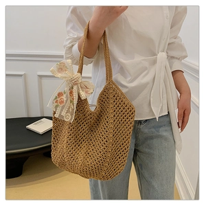 Detail view of woven straw tote bag with floral lace scarf and hollow mesh texture