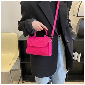 Close-up of bright magenta crocodile pattern handbag showing rich texture and metal strap