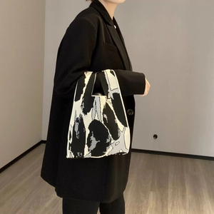 Detail of a knitted tote bag featuring a black and white abstract pattern in a casual style