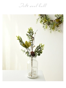 Detail of pine needles, wool balls and pine cones in a glass jar for Christmas decor