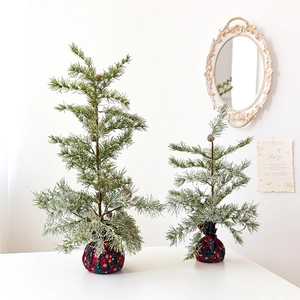 Miniature cedar Christmas trees with pine cones and festive red patterned bases
