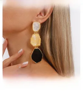 Macro detail of geometric resin earrings with white yellow and black irregular panels