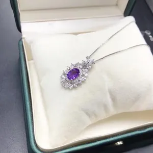 Détail du collier améthyste avec monture florale en argent dans un écrin vert luxueux