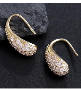 Detailed view of curved teardrop hook earrings with pavé-set zircons on dark rock