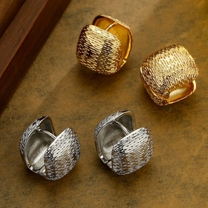 Macro shot of textured gold and silver metal hoop earrings on stone background