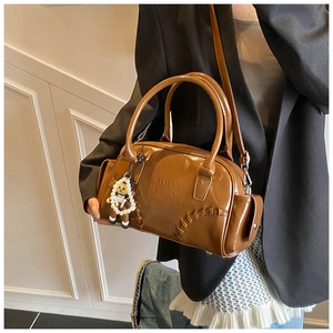 Brown patent leather bowling bag detail with embossed lettering and pearl bear charm