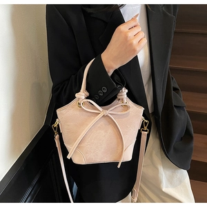 Détail du sac seau élégant abricot avec nœud décoratif et poignée nouée sophistiquée