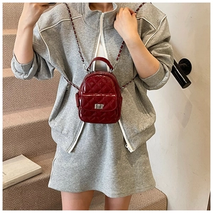 Detail view of wine red quilted patent leather mini backpack with silver chain strap
