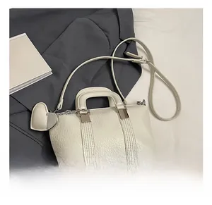 Close-up of white lychee pattern leather handbag with silver hardware and heart pendant