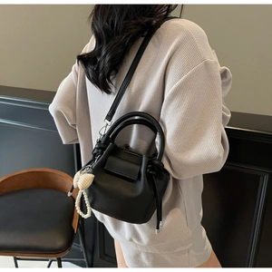 Detail of black lychee grain leather bucket bag with heart pendant and pearl chain